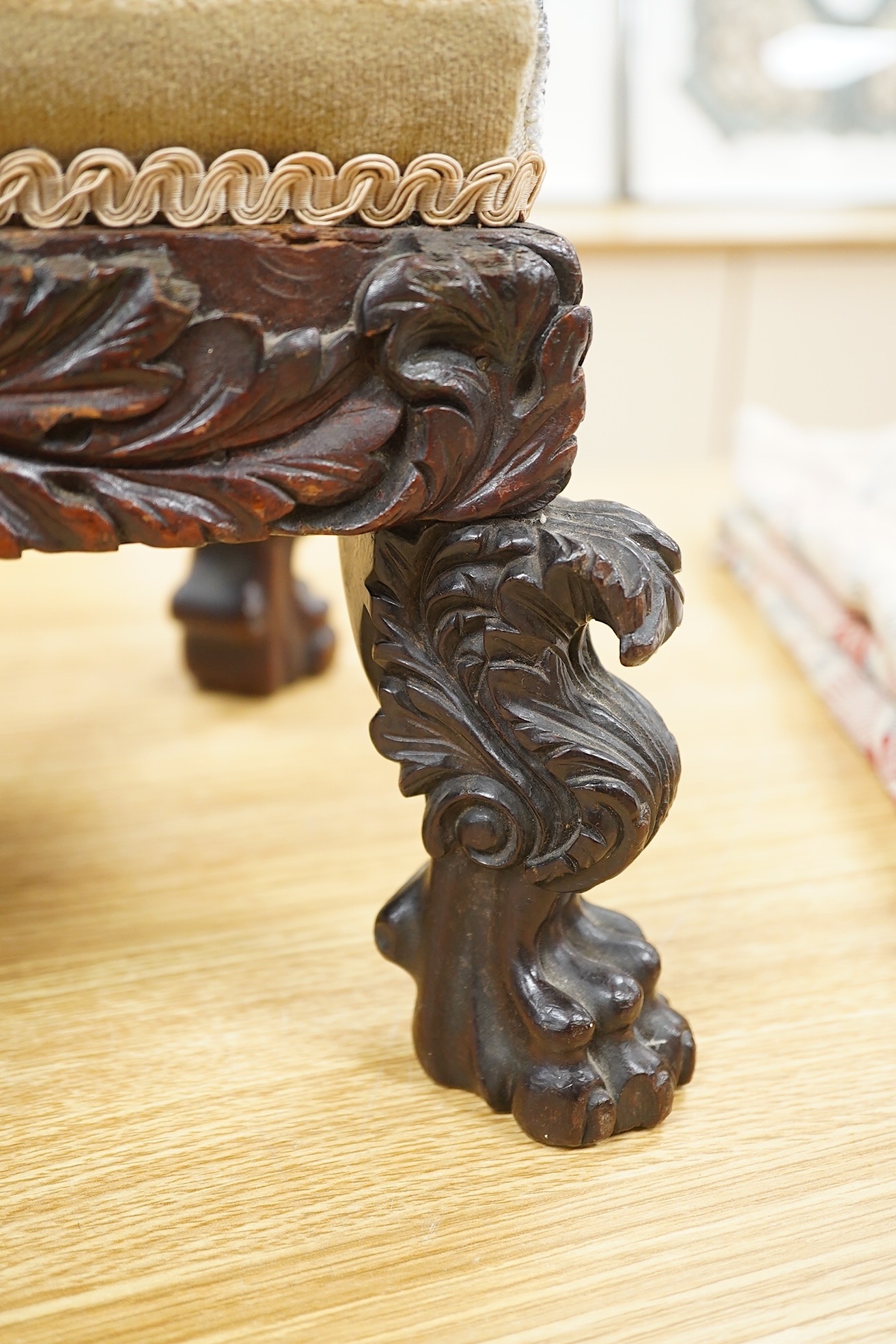 A 19th century ornately carved paw foot, Berlin beadwork upholstered footstool, the bead work a scrolling multi-coloured floral pattern, upholstered into a heavily carved frame and legs on carved paw feet, beadwork 21cm